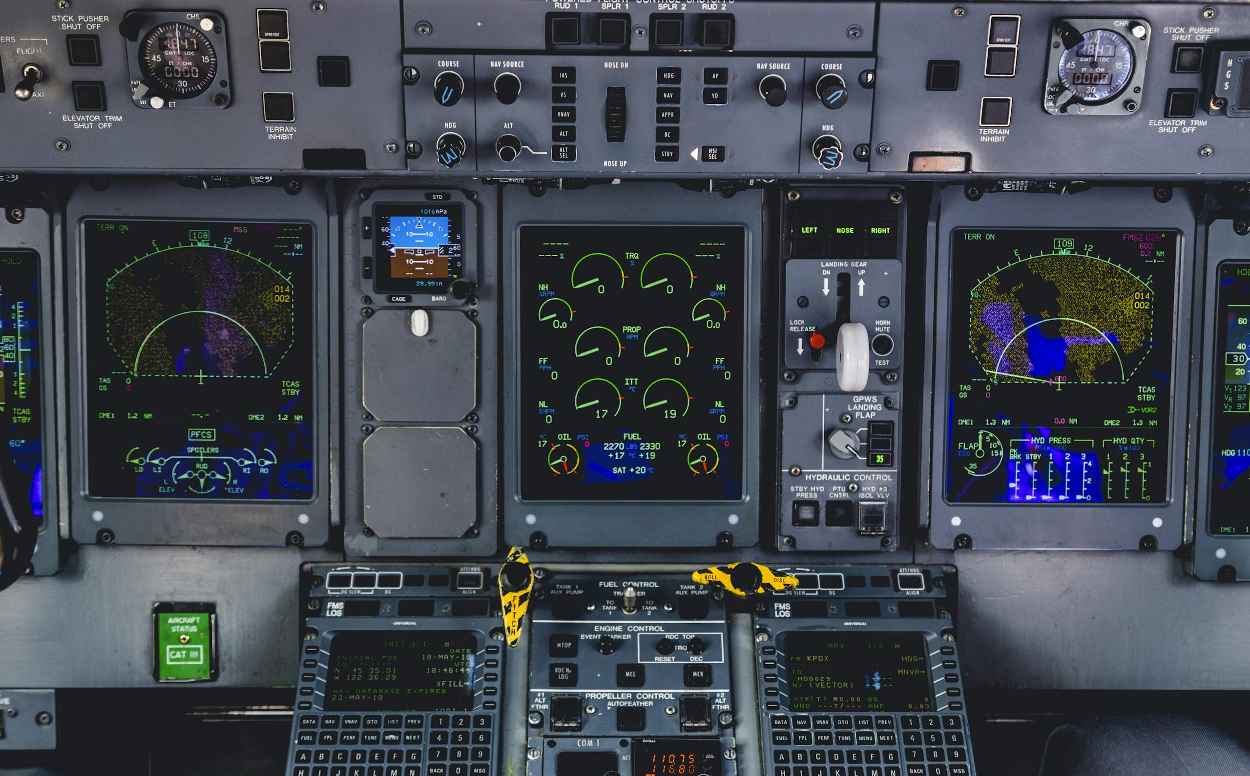 Detailed view of an aircraft cockpit control panel with various screens and controls.