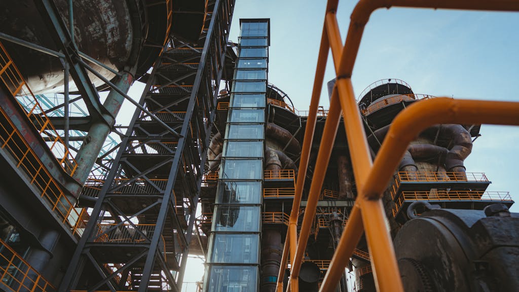 Low angle view of an industrial elevator and complex metal structures with pipes.