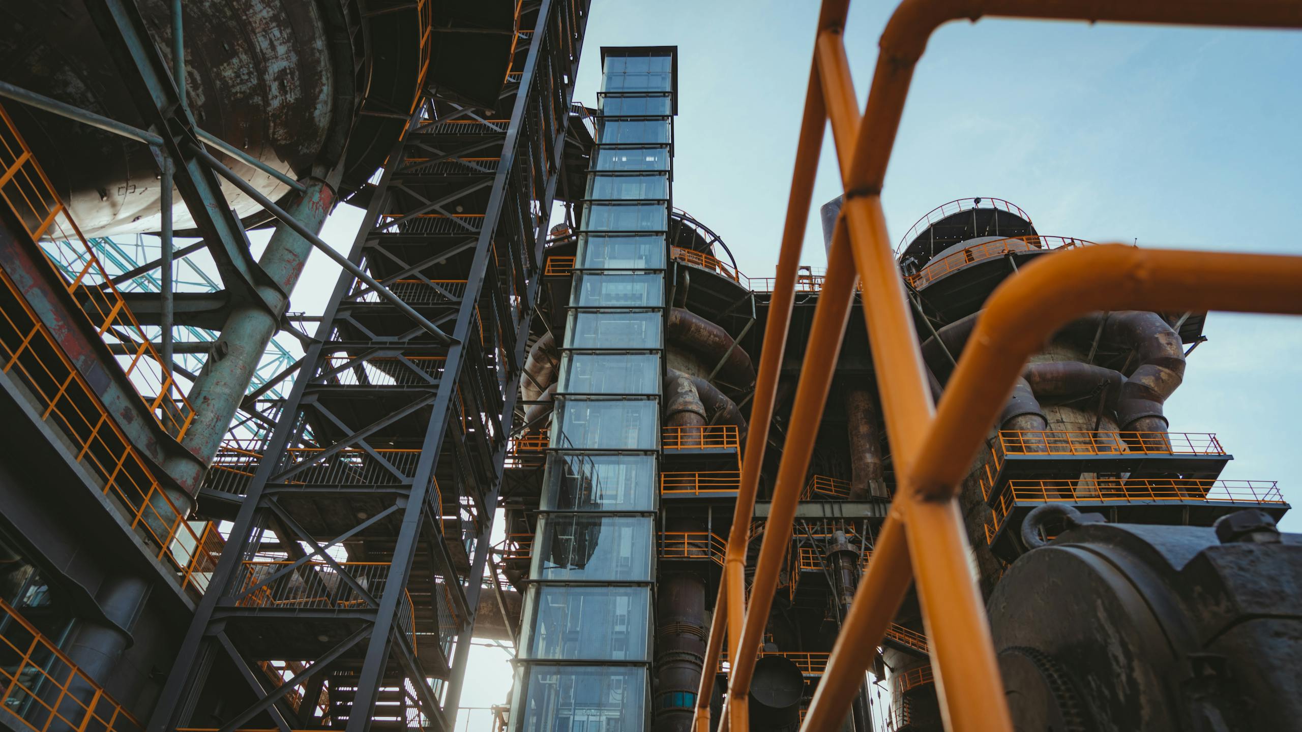 Low angle view of an industrial elevator and complex metal structures with pipes.