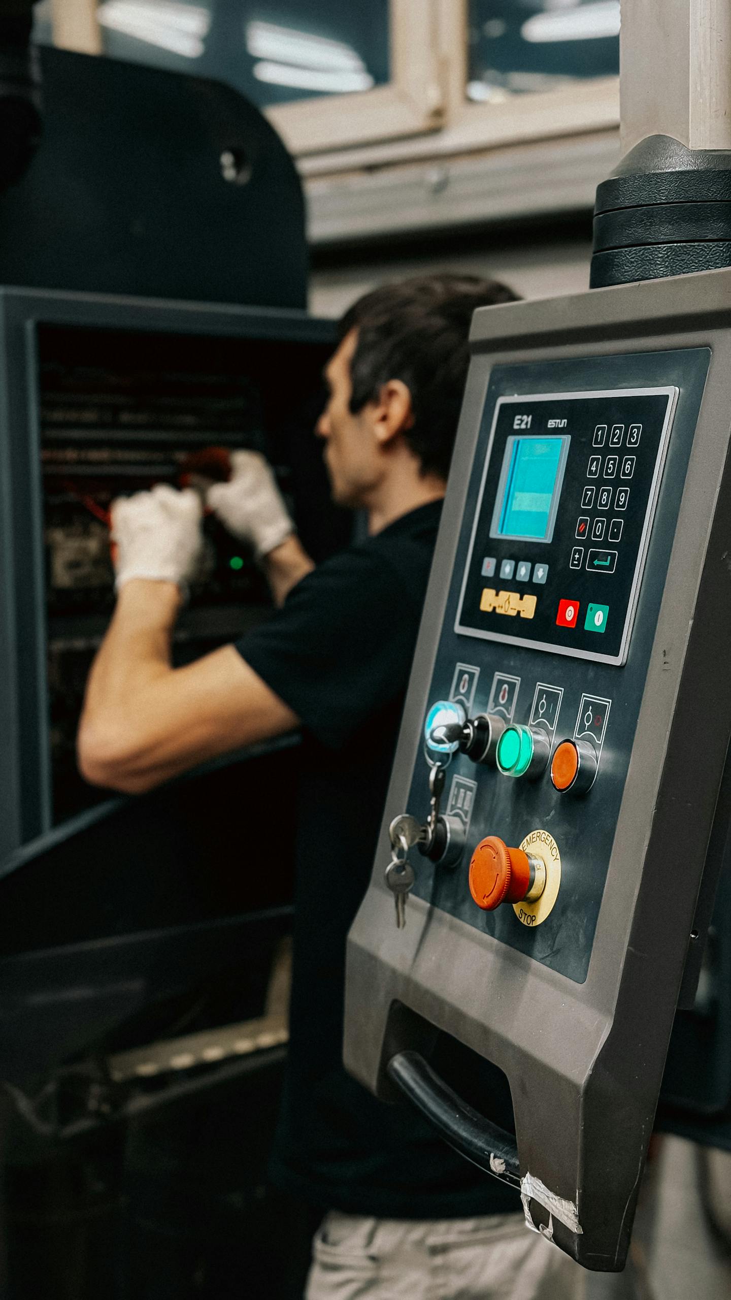 Technician using a control panel to manage machinery operations in a factory.