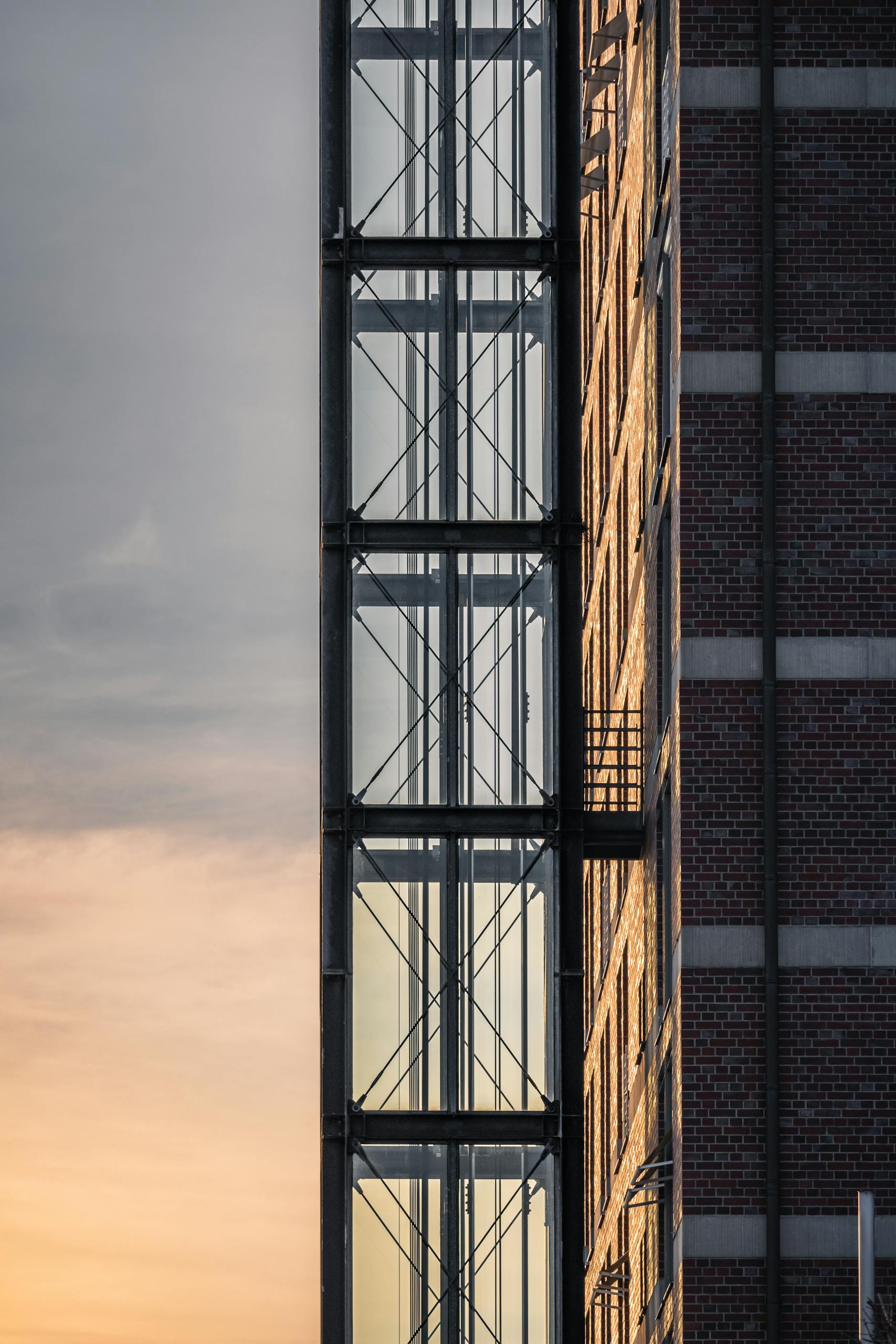 Vertical shot of a building facade with a glass elevator during sunset in Hamburg.